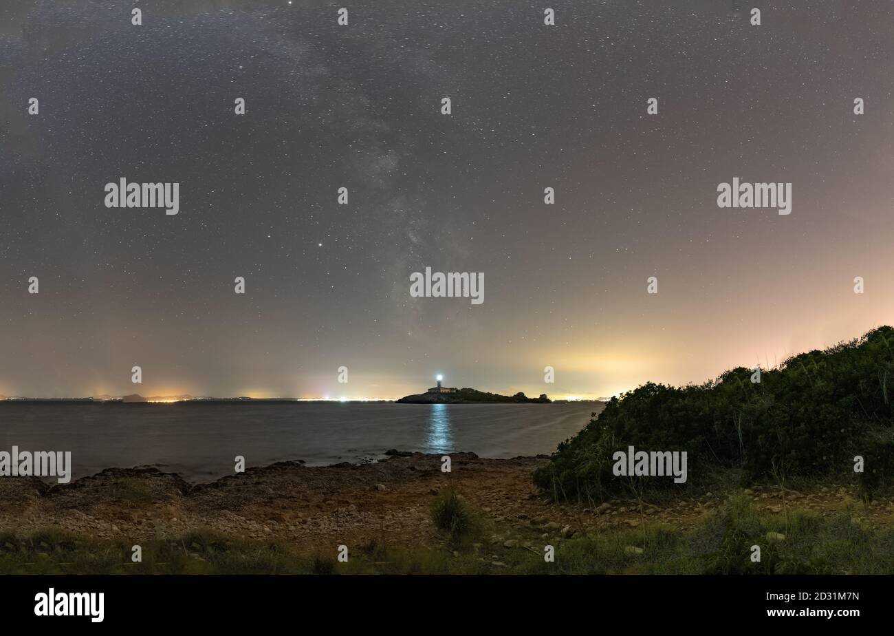 Milky Way au-dessus du phare d'Aucanada, dans la baie d'Alcudia, Majorque, Espagne, pendant une nuit d'été et ciel clair. Image prise de la plage. Banque D'Images