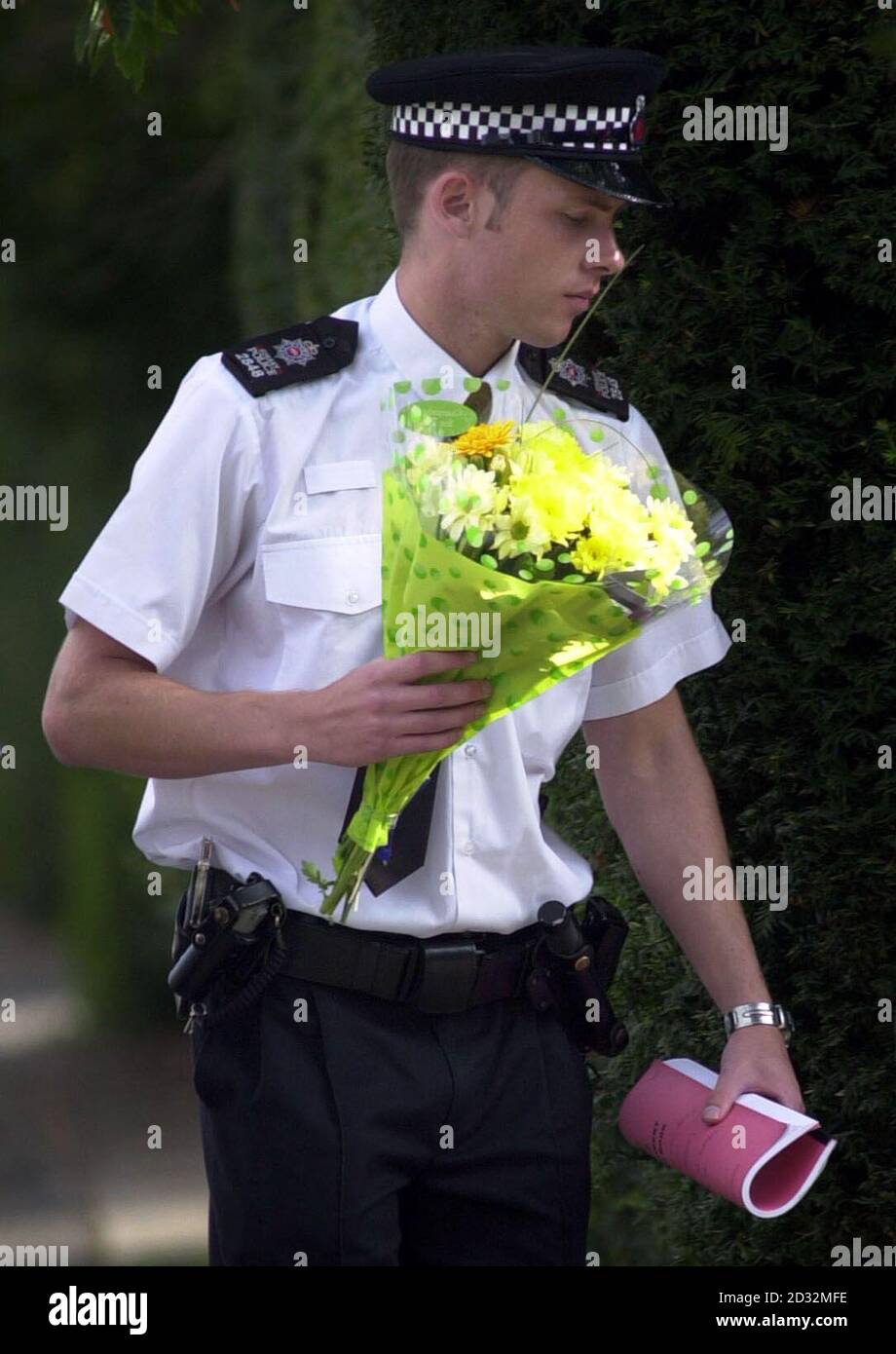 Un policier transporte des fleurs dans la maison des parents de la jeune fille Amanda Dowler assassinée à Walton-nn Thames, dans le Surrey, dont le corps a été trouvé dans les bois du Hampshire. Banque D'Images