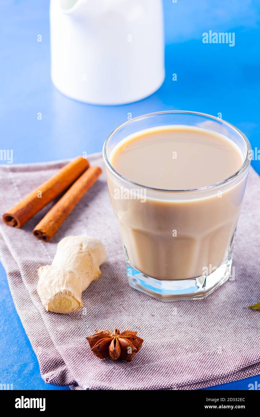 Thé au chaï masala sur une serviette en lin. Boisson traditionnelle indienne - thé masala avec diverses épices. Verre de thé masala sur fond bleu Banque D'Images