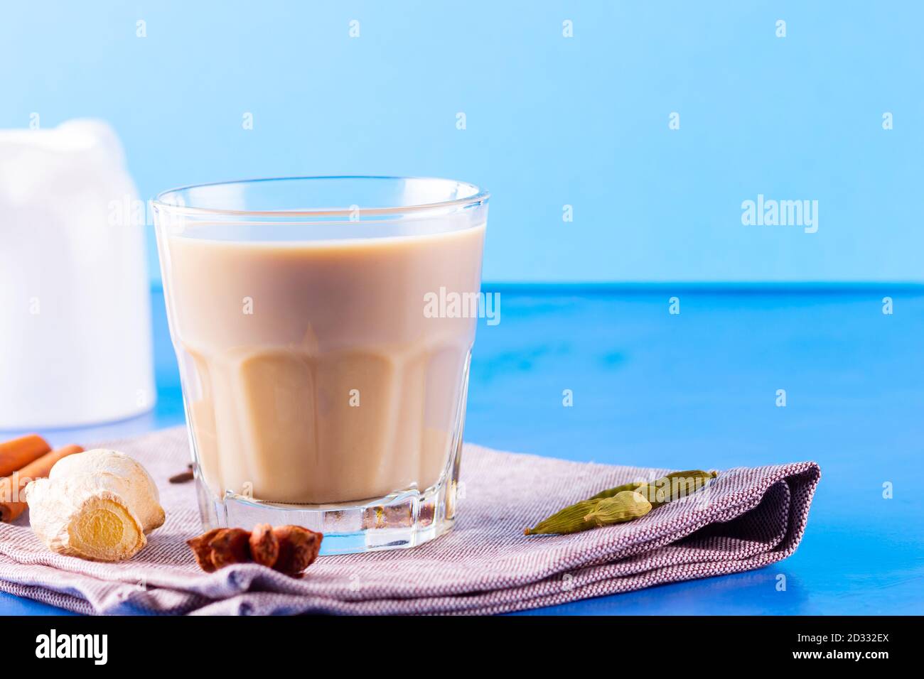 Thé au chaï masala sur une serviette en lin. Boisson traditionnelle indienne - thé masala avec diverses épices. Verre de thé masala sur fond bleu Banque D'Images