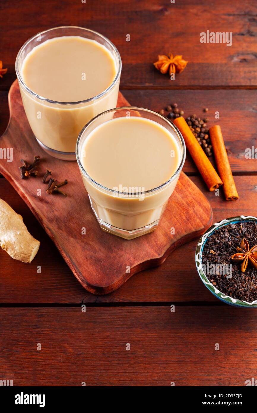 Thé au lait et épices. Thé Chai au masala sur des planches en bois. Deux verres de thé masala et des ingrédients pour le préparer. Copier l'espace. Vue de dessus Banque D'Images