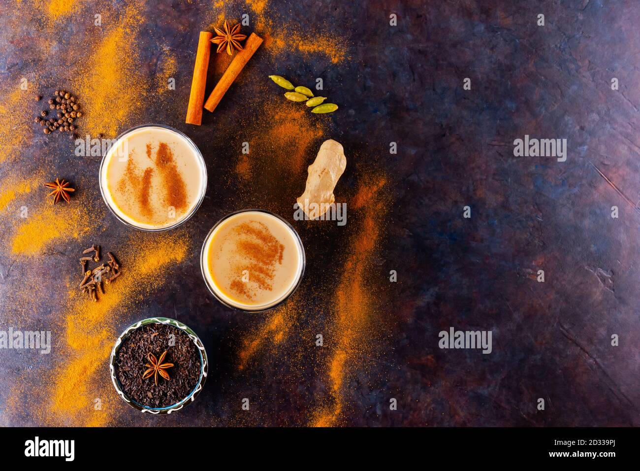 Thé Chai de masala sur fond noir. Deux verres transparents de thé masala et diverses épices éparpillées. Vue de dessus Banque D'Images