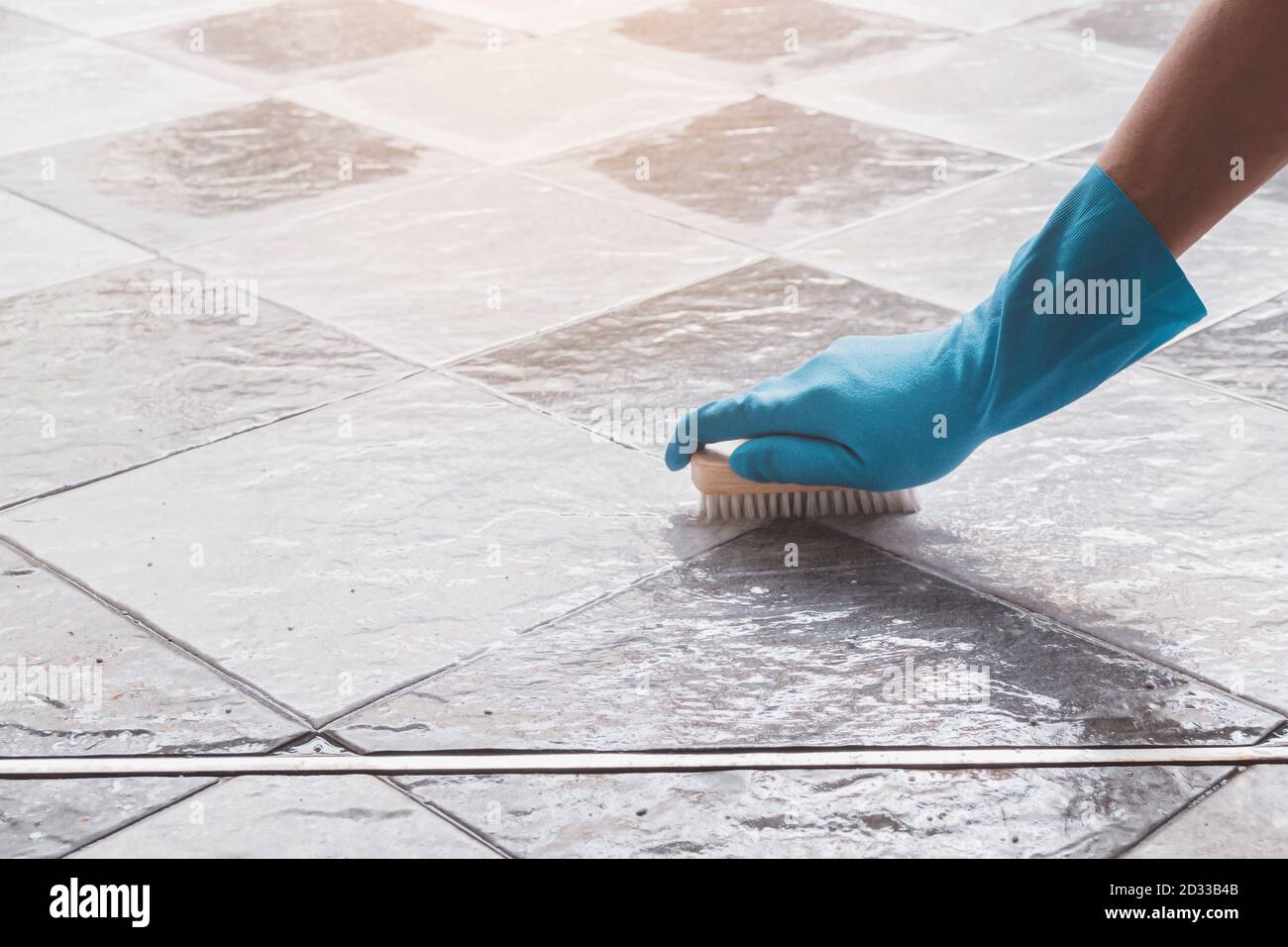 La main de l'homme portant des gants en caoutchouc bleu est utilisée pour convertir le nettoyage à l'aide d'un nettoyeur sur le sol carrelé. Banque D'Images La main de l'homme portant des gants en caoutchouc bleu est utilisée pour convertir le nettoyage à l'aide d'un nettoyeur sur le sol carrelé. Banque D'Images