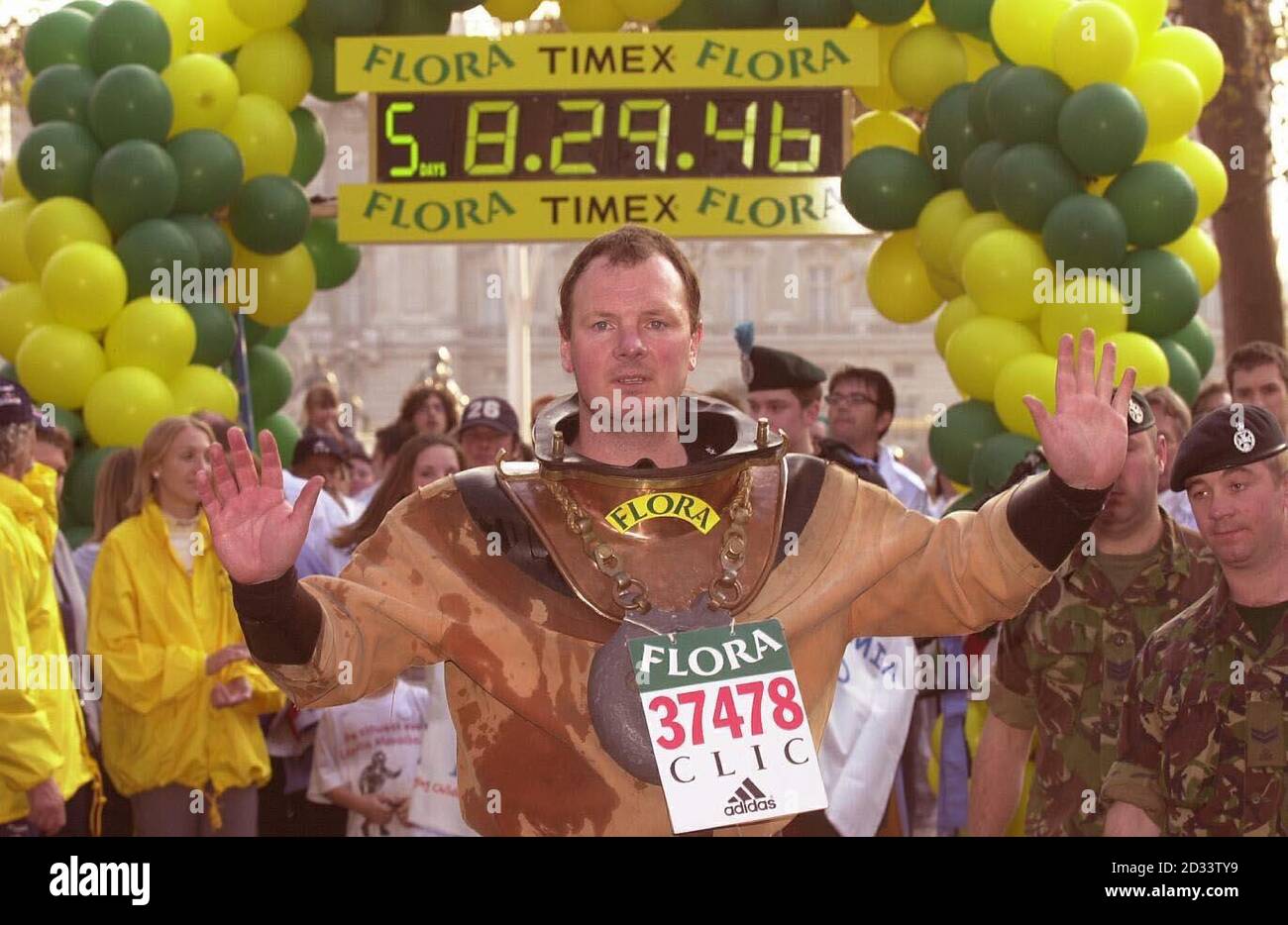 Lloyd Scott franchit la ligne d'arrivée du marathon de Londres, Lloyd, le coureur de marathan le plus lent de l'histoire, a 'couru' le parcours portant un costume de plongée antique en six jours. Lloyd espère avoir grandi dans la région de 100,000 en faveur du cancer et de la leucémie dans l'enfance grâce à ses efforts. Banque D'Images