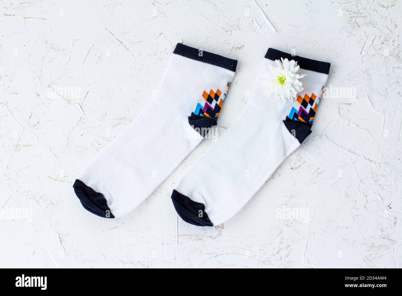 Paire de chaussettes pour femmes et fleur d'aster sur fond blanc structuré, vue du dessus. Banque D'Images