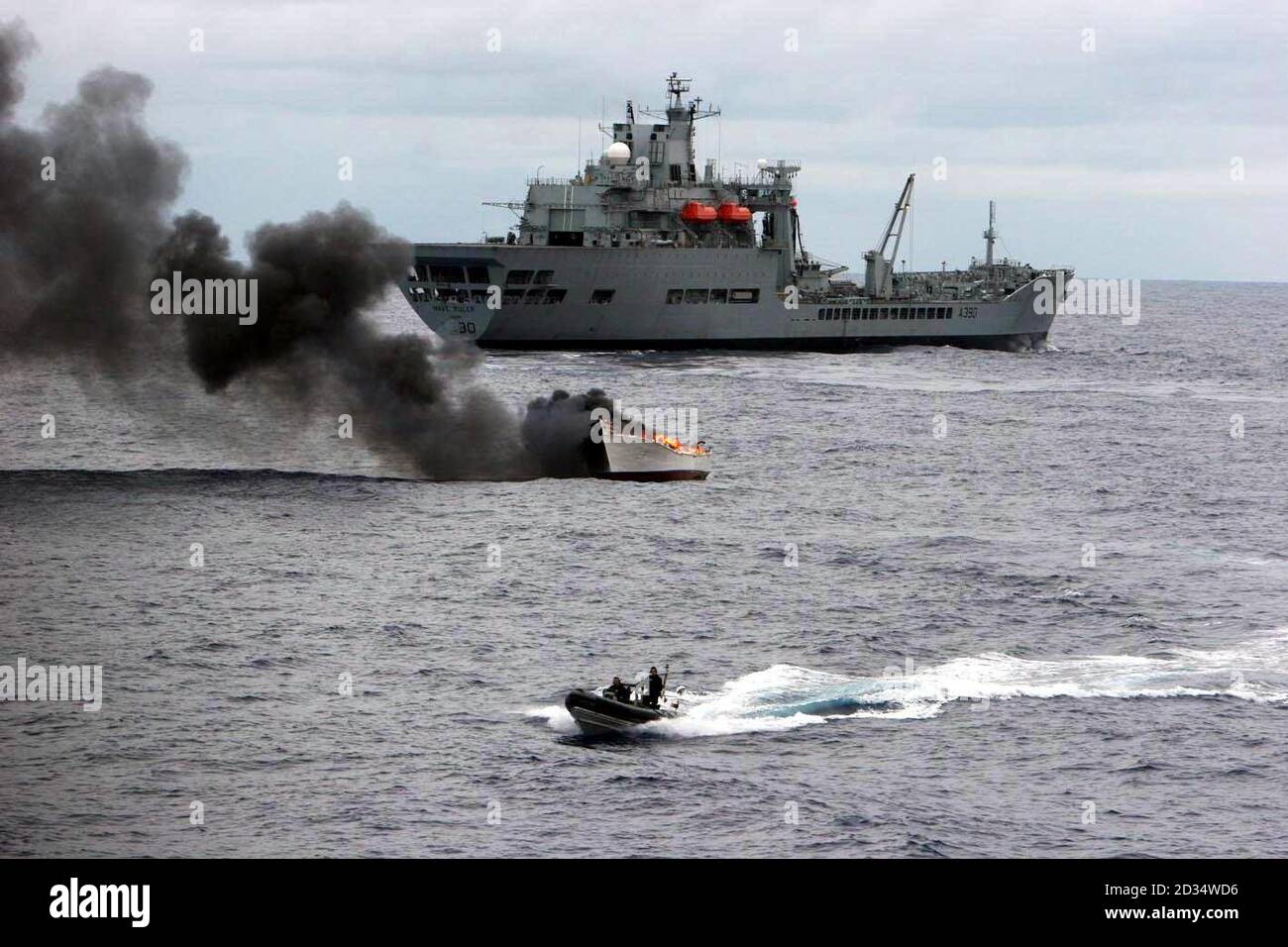 Un bateau transportant jusqu'à cinq tonnes de cocaïne - d'une valeur marchande estimée à 500 millions de livres - brûle dans les Caraïbes après avoir été pris par le navire auxiliaire de la flotte royale RFA Wave Ruler (arrière-plan) après une poursuite de nuit. Banque D'Images