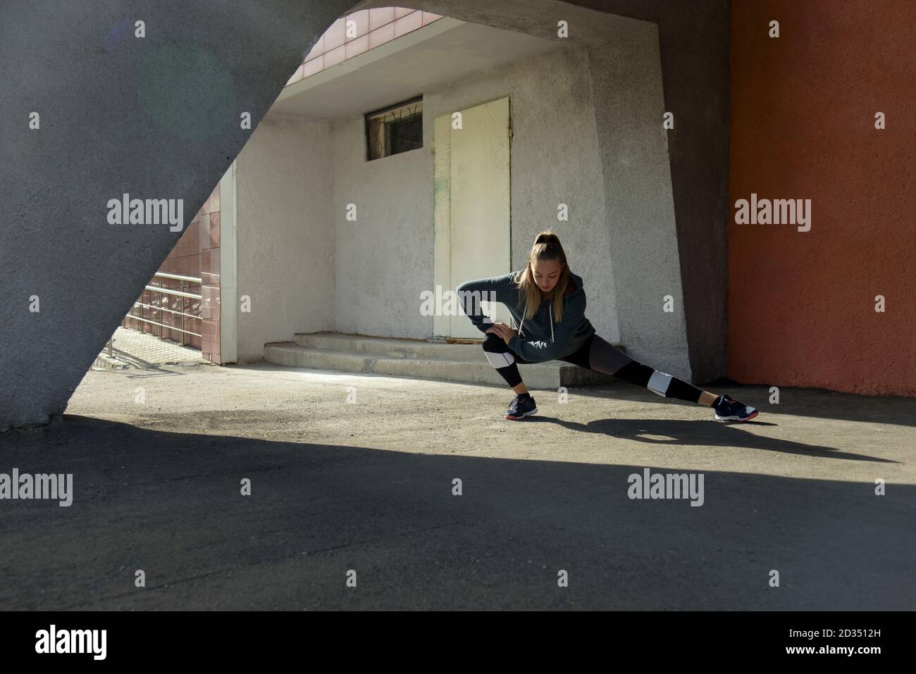 Femme de fitness s'étirant à l'extérieur dans un environnement urbain Banque D'Images