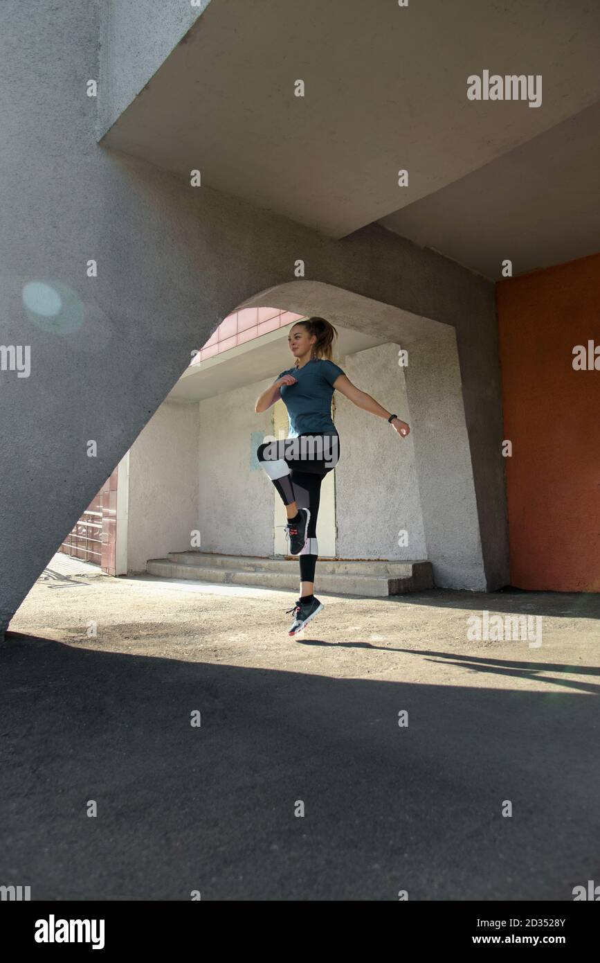 Femme de fitness sautant à l'extérieur dans un environnement urbain Banque D'Images