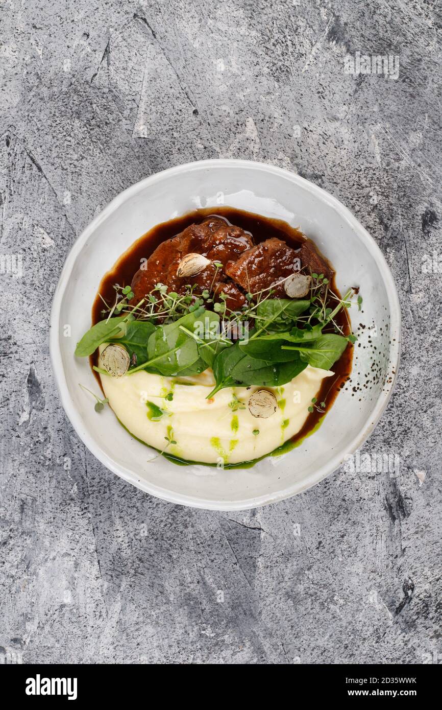 Joues de veau en sauce avec pommes de terre et chou, décorées avec des herbes Banque D'Images