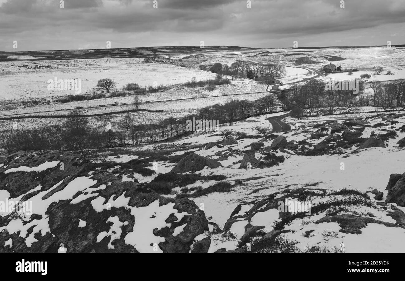 North York Maures après une chute de neige avec des rochers, de la bruyère, des arbres et une ferme sous un ciel nuageux en hiver près de Goathland, Yorkshire, Royaume-Uni. Banque D'Images