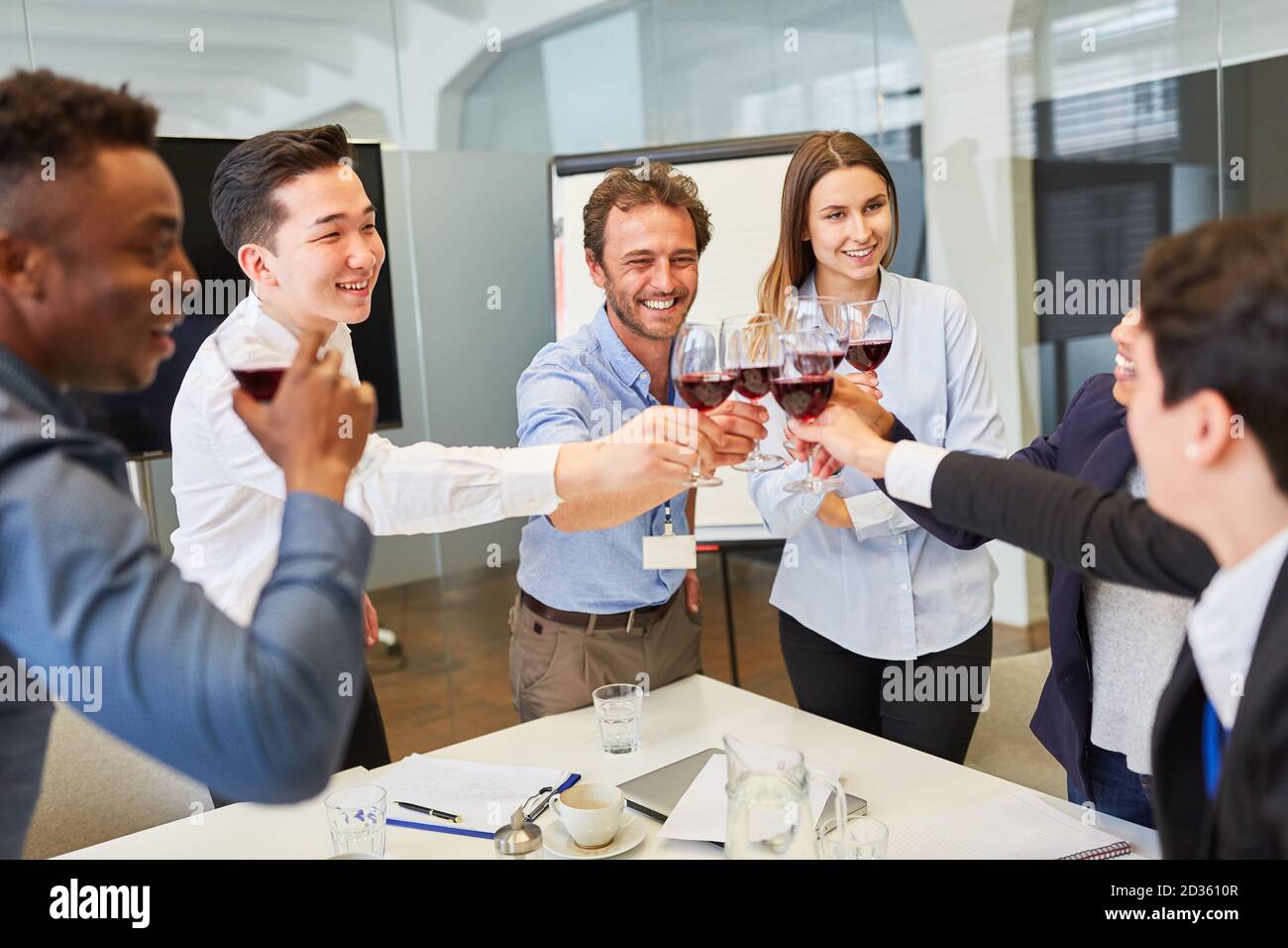 Une jeune équipe de start-up toaster avec un verre de vin rouge à une fête de la société Banque D'Images