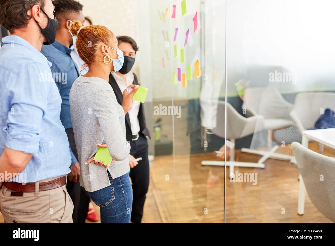 Équipe créative avec masque facial dans un atelier de brainstorming ou séminaire Banque D'Images