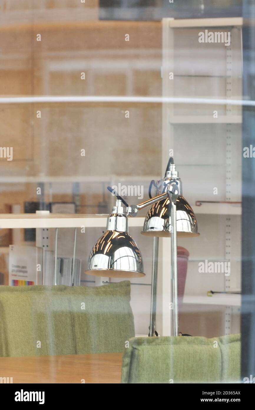 Une lampe de table argentée sur une table de la bibliothèque. Vue à travers la vitre. Banque D'Images