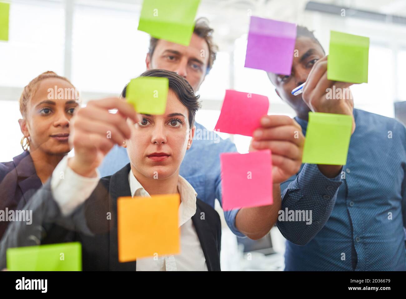 L'équipe de création regarde ensemble les notes adhésives sur le verre dans le séminaire de brainstorming Banque D'Images