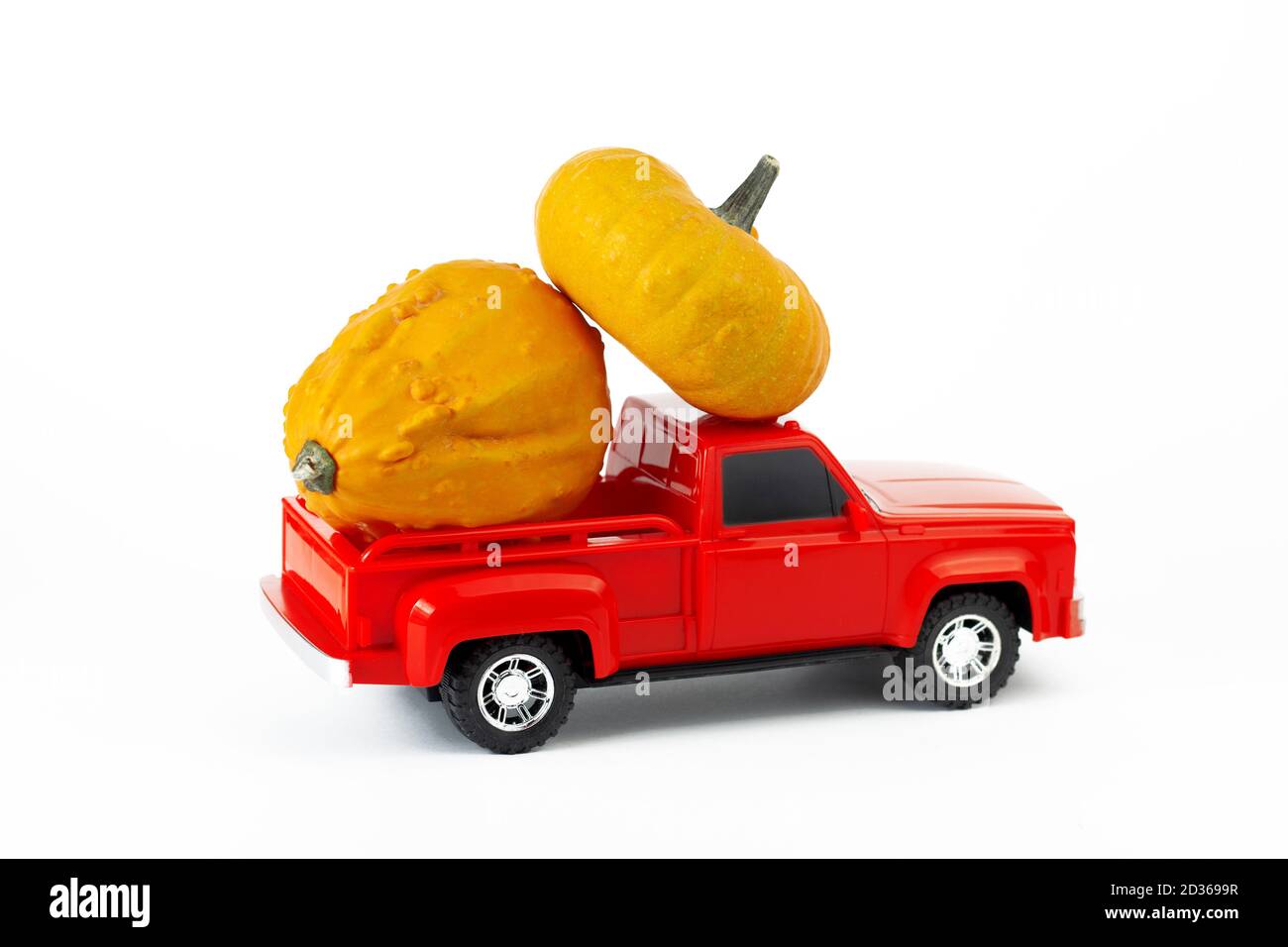 Concept de récolte d'automne. Citrouilles décoratives jaunes dans le coffre de pick-up rouge à la mode. Banque D'Images