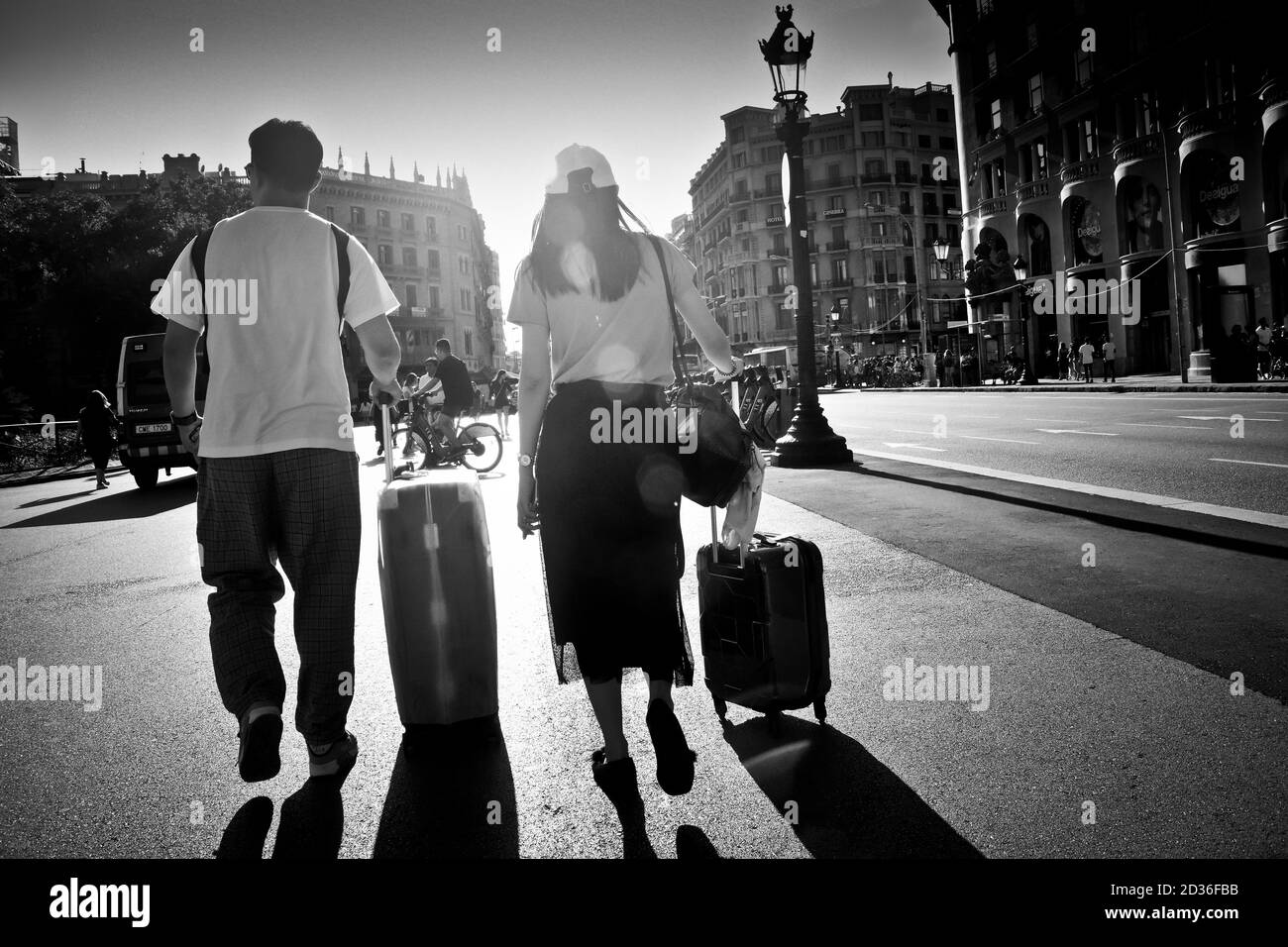 Homme et femme marchant dans une rue avec leurs valises à roulettes. Banque D'Images Homme et femme marchant dans une rue avec leurs valises à roulettes. Banque D'Images