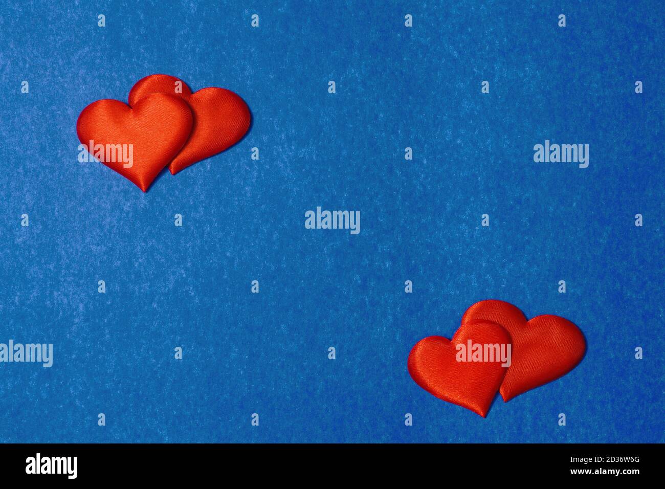 Deux paires de coeurs rouges sur fond de carton de couleur bleue classique. Espace de copie pour le texte, concept de jour de Saint-Valentin, vue de dessus Banque D'Images