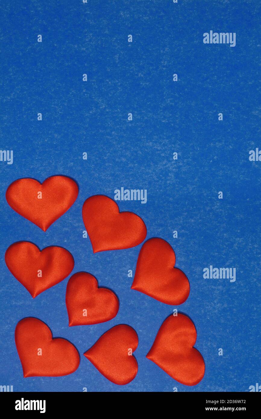 Vue verticale du dessus des coeurs rouges dans le coin sur fond de carton bleu. Concept de la Saint-Valentin, espace de copie Banque D'Images