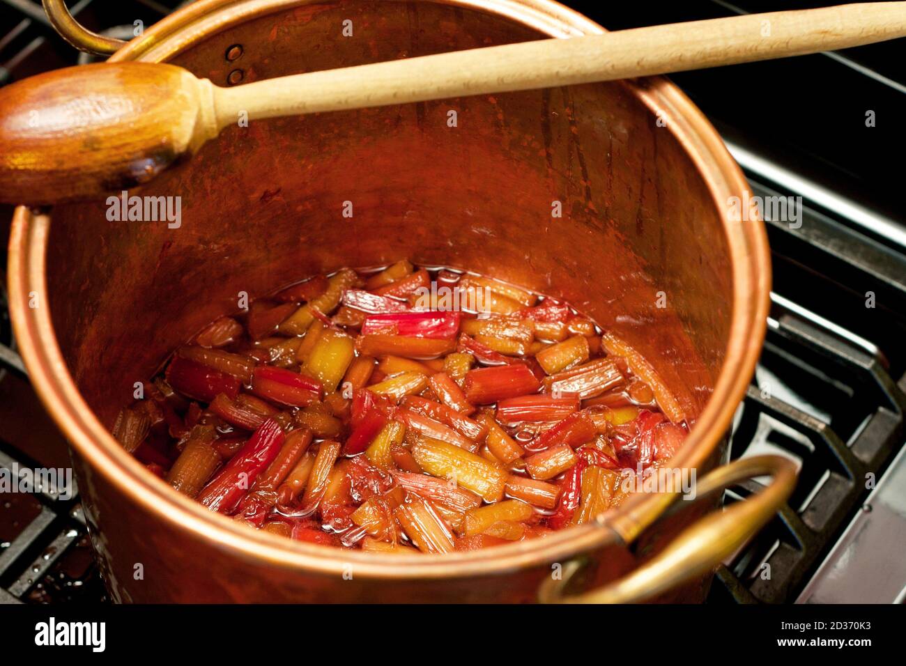 Le rhubarbe couve dans un pot de cuivre sur le poêle. Banque D'Images