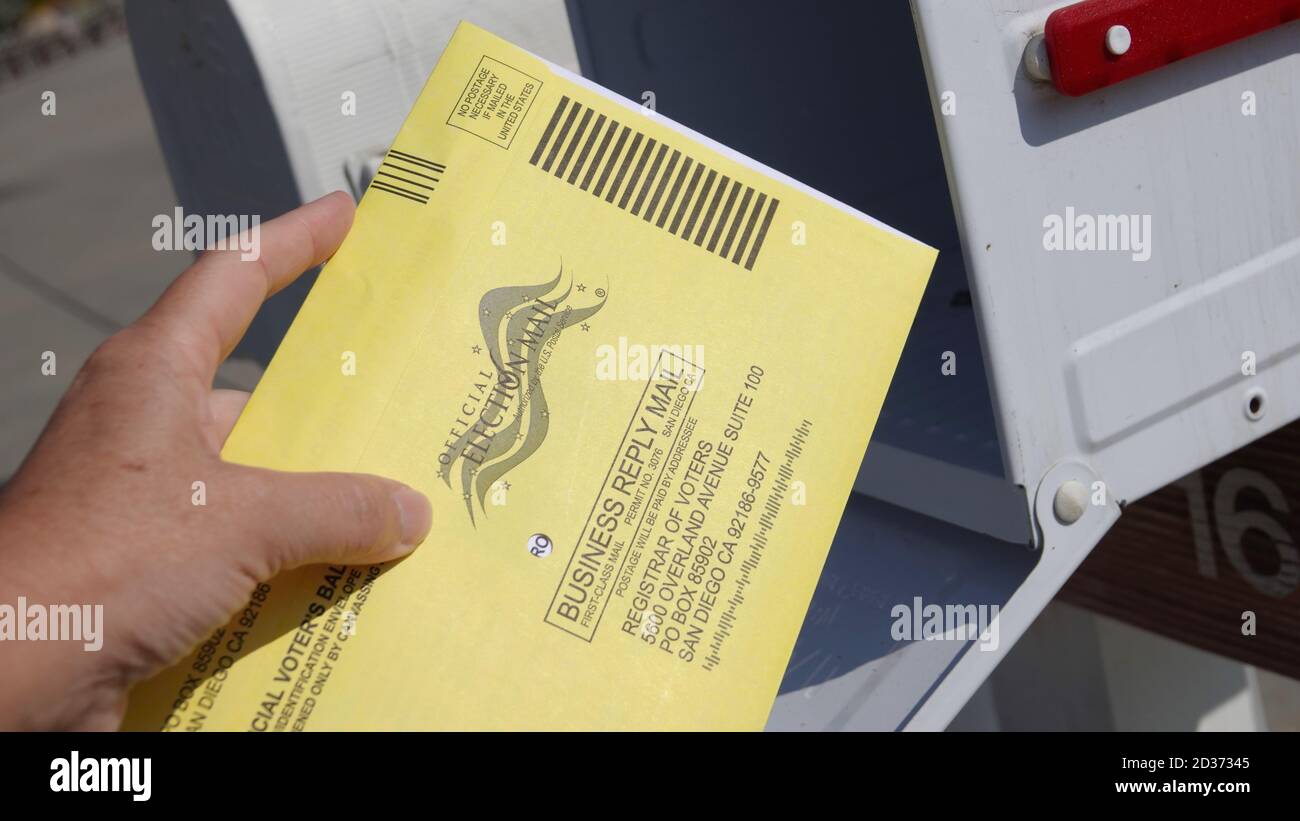 Gros plan de la main d'une femme retournant son bulletin de vote par courrier, le mettant dans la boîte postale. Éditorial illustré pris dans Vista, CA / USA le 7 octobre 2020. Banque D'Images