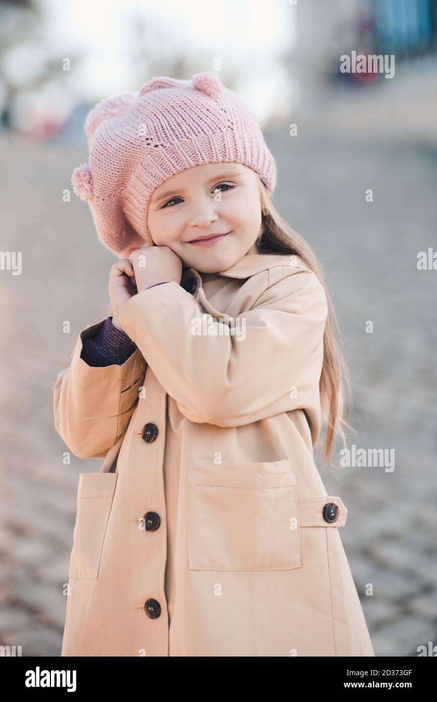 Sourire mignonne bébé fille de 3-4 ans portant un chapeau tricoté et un manteau  d'hiver beige posant dans le parc à l'extérieur gros plan. Enfance.  Bonheur. Saison d'automne Photo Stock - Alamy