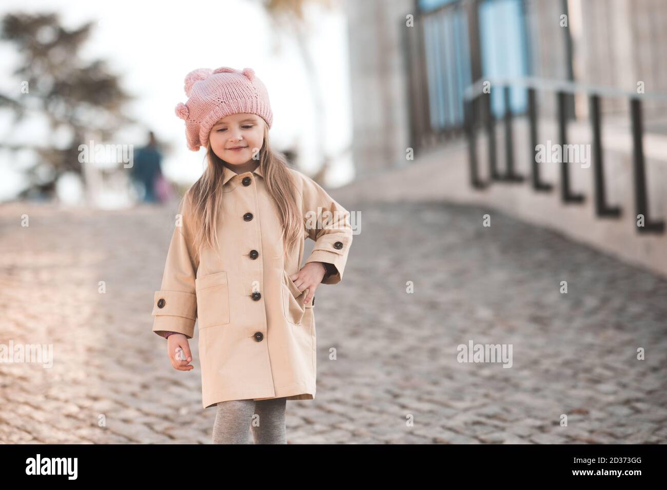 Élégant blond enfant fille 3-4 ans porter des vêtements décontractés:  Bonnet tricoté et beige hiver manteau marcher dans le parc à l'extérieur de  près. Enfance. Automne se Photo Stock - Alamy
