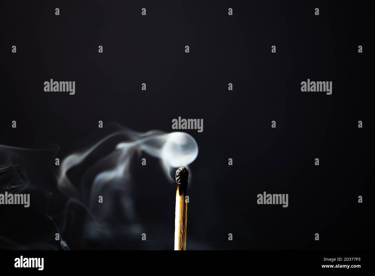 Un match en bois non éclairé qui dégage de la fumée sur fond noir Banque D'Images