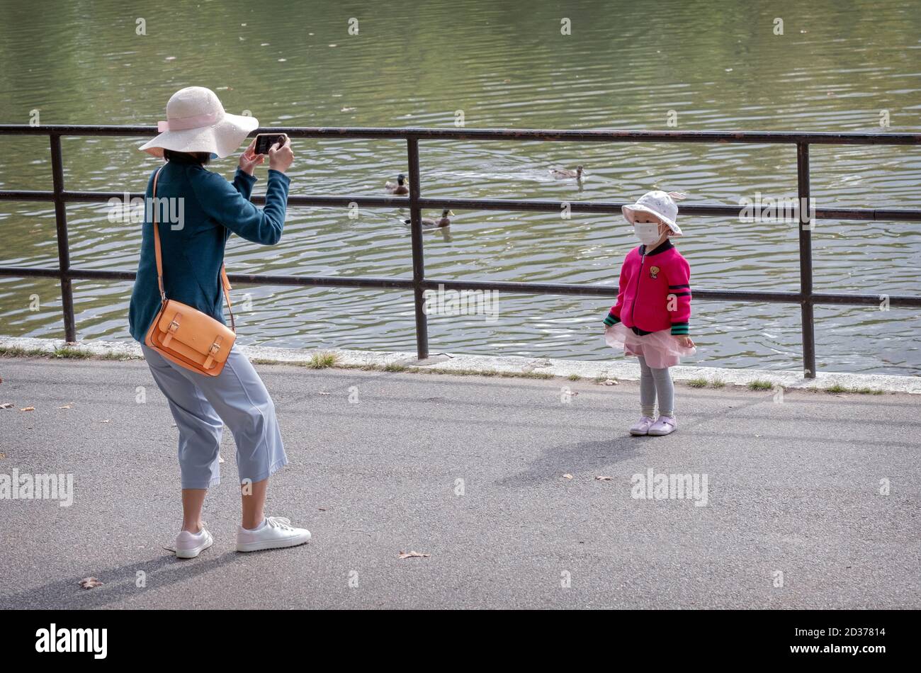 Une mère prend des photos de sa petite fille très mignonne sur son téléphone portable. À Kissena Park, Flushing, Queens, New York City.Wears, port Banque D'Images