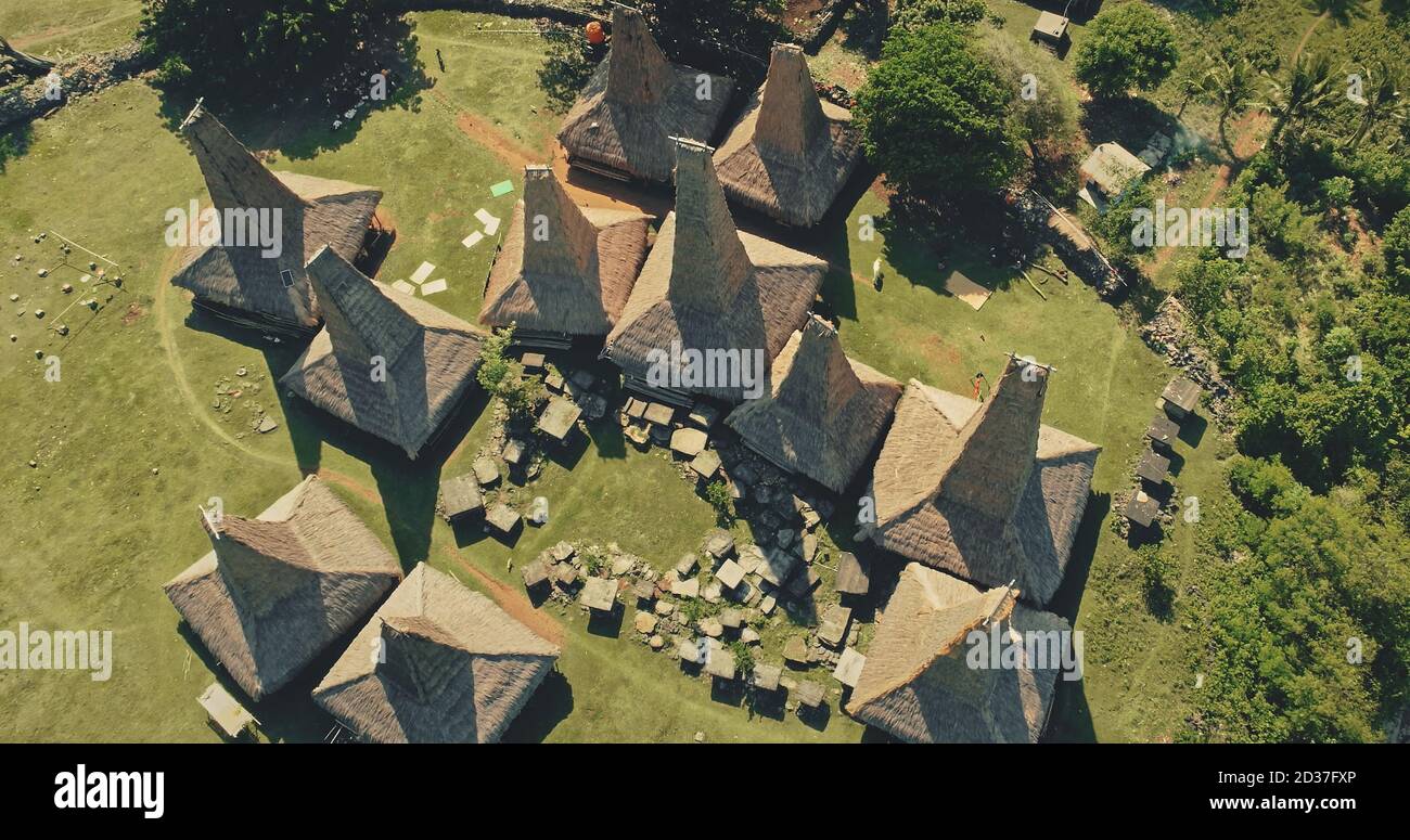 Haut en bas de touristes tour dans les maisons traditionnelles toits de village primitif sur l'île de Sumba, Indonésie. Des vacances d'été incroyables admiratifs vert nature sauvage et unique monument indonésien à la prise de drone Banque D'Images