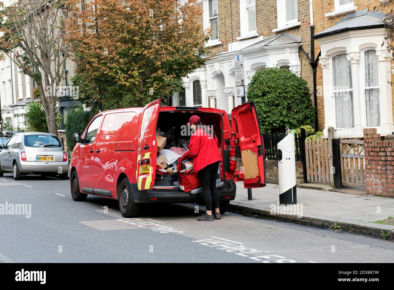 Femme de poste ou femme de poste sélectionnant des colis à l'arrière de la livraison de Royal Mail van Highbury, London Borough of Islington Banque D'Images