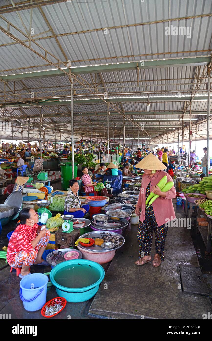 CAN TH, VIETNAM - 19 mars 2014: Une dame qui porte des légumes regarde le poisson dans le marché couvert, à CAN Tho, dans le sud du Vietnam, sur la rivière MEK Banque D'Images