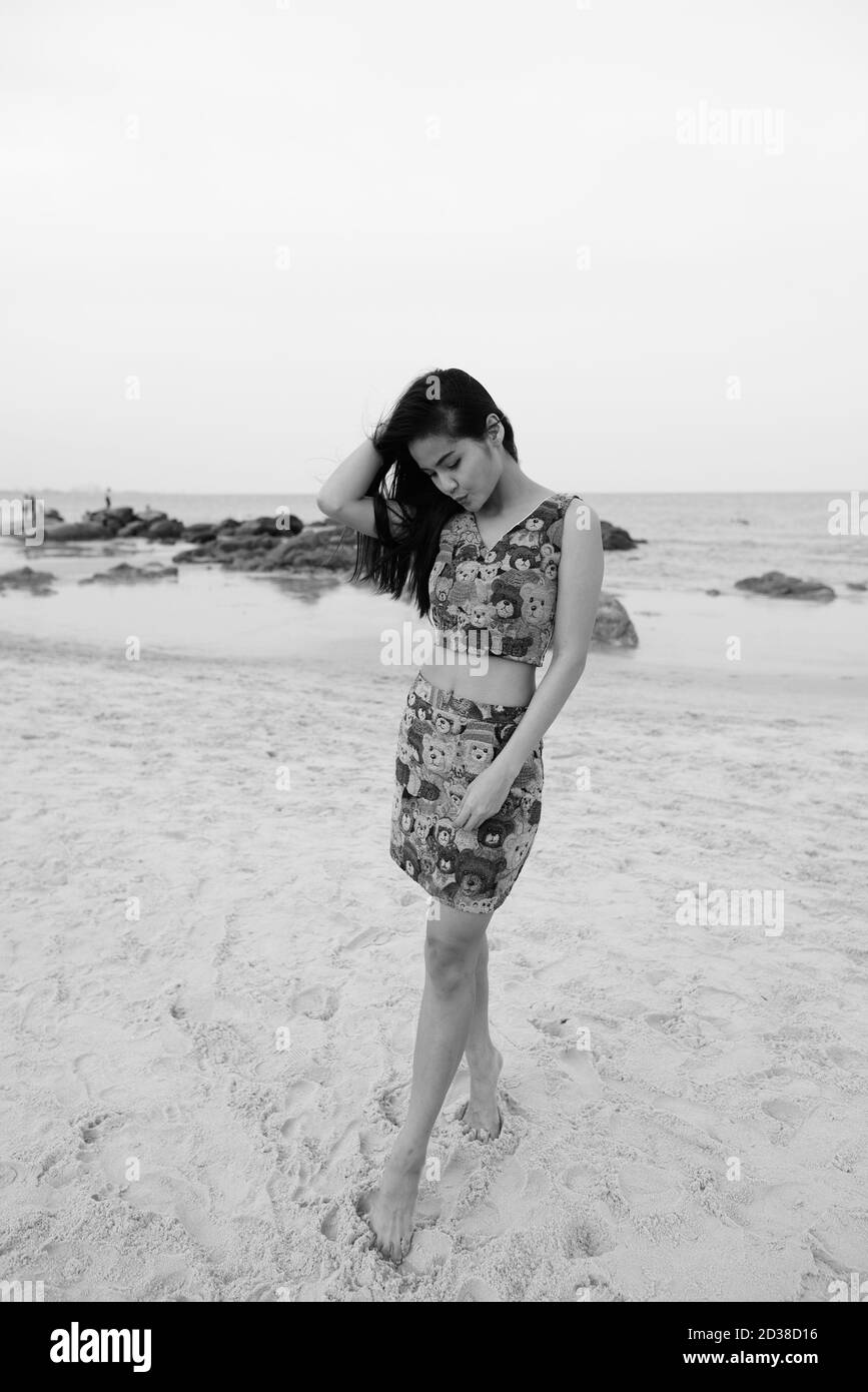Belle jeune femme asiatique à la recherche vers le bas et jouer avec le sable à la plage publique de Hua Hin en Thaïlande Banque D'Images Belle jeune femme asiatique à la recherche vers le bas et jouer avec le sable à la plage publique de Hua Hin en Thaïlande Banque D'Images