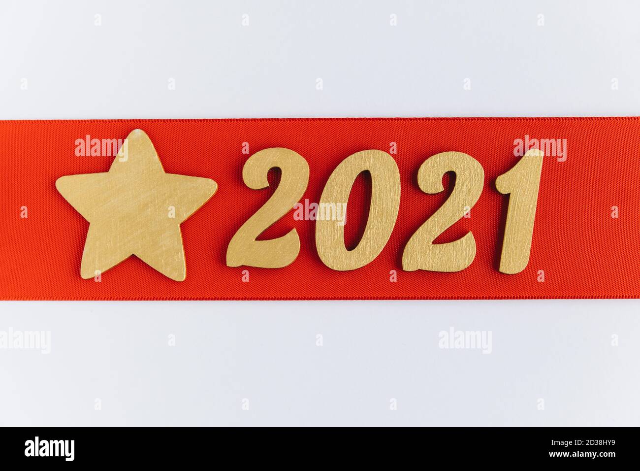 Fond festif. Ruban rouge avec signe doré du nouvel an 2021 et étoile. Bannière de fête des fêtes d'hiver. Joyeux Noël et Bonne Année. Banque D'Images