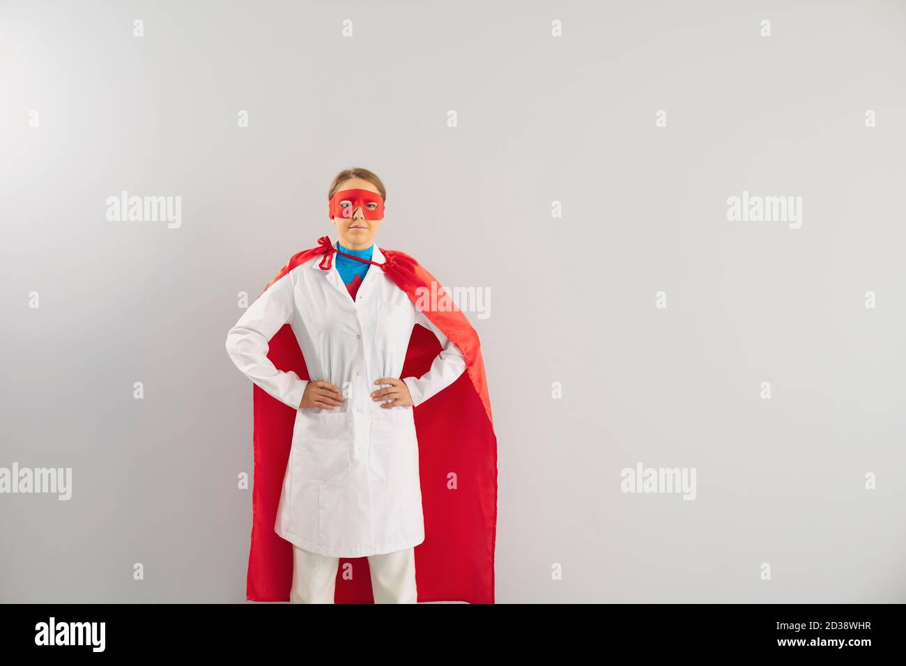 Femme médecin en costume de super-héros sur fond gris. Une superfemme en cape rouge et un masque protégeant la santé publique Banque D'Images
