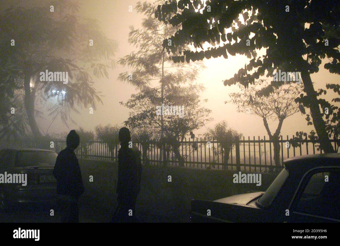 Les Indiens se tiennent dans un brouillard épais lors d'une soirée froide à New Delhi le 17 janvier 2003. Le nombre de morts a atteint 1,100 vendredi dans un climat froid qui a blanchi l'Asie du Sud avec du gel et du brouillard et a paralysé la circulation aérienne, routière et ferroviaire. Photo prise le 17 janvier 2003. REUTERS/B. Mathur JSG/FA Banque D'Images