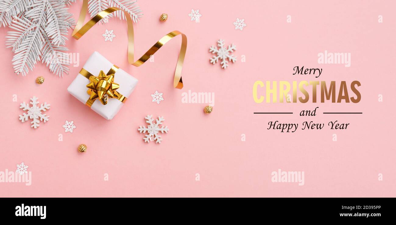 Cadeau de Noël, décorations dorées sur fond rose pastel Banque D'Images