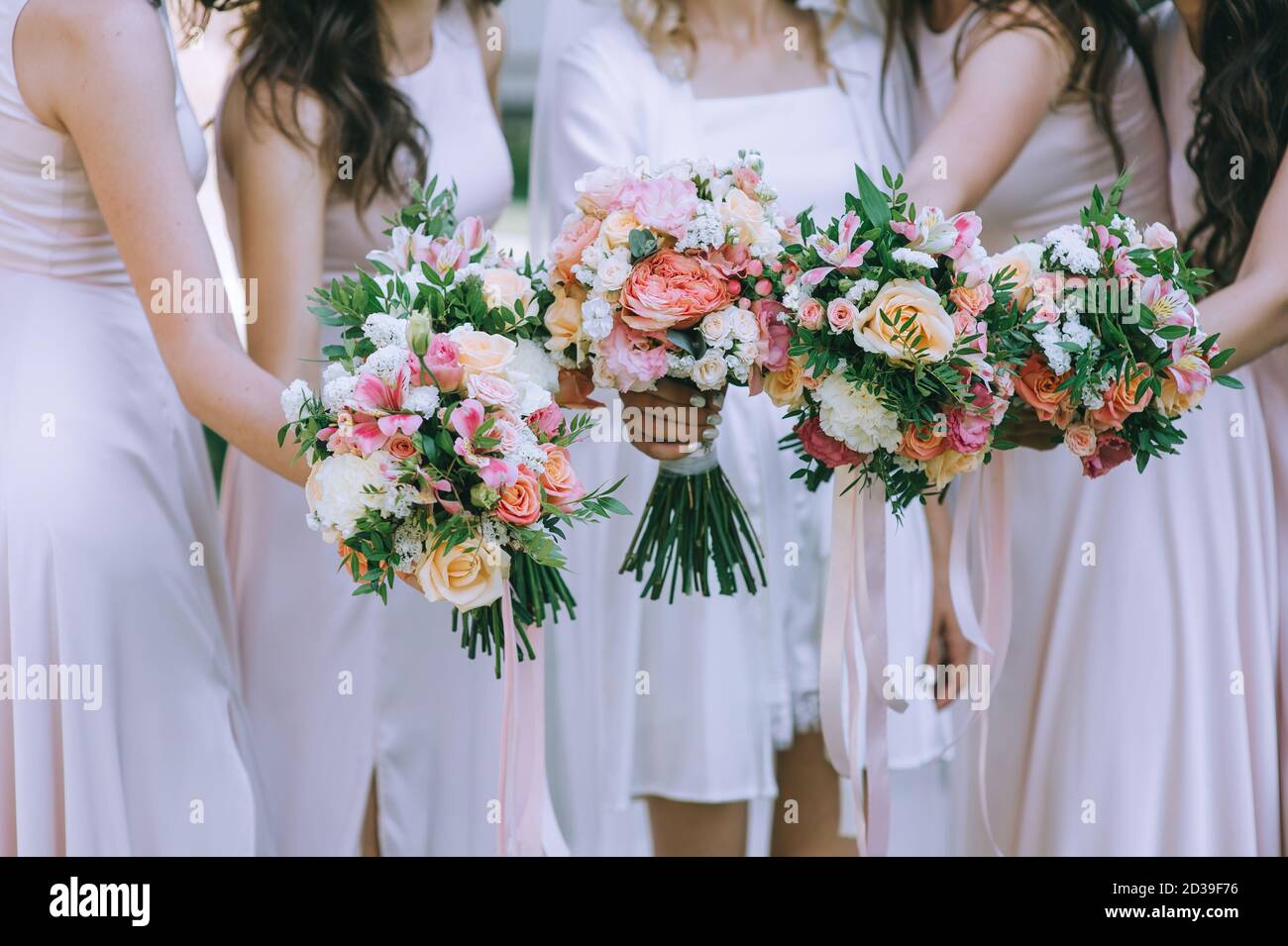 Image rognée de la demoiselle d'honneur et de la mariée d'une mariée sans visage vêtue de robes blanches en satin tenant de beaux bouquets de mariage. Matin de la mariée. Weddin Banque D'Images