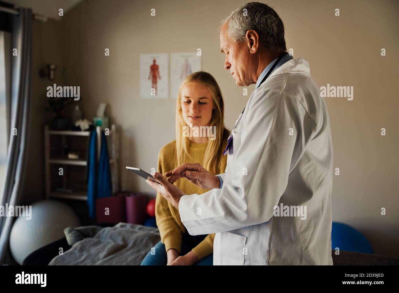 Médecin de sexe masculin parlant aux patientes des résultats des analyses de sang, assis sur un lit pliant dans un bureau moderne. Banque D'Images