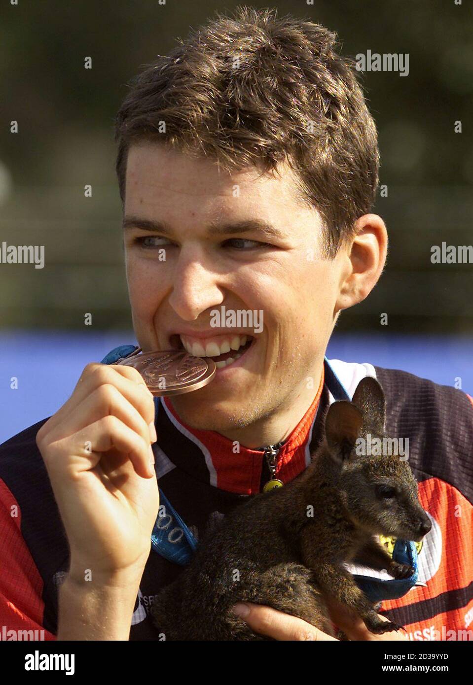 Christoph Sauser De Suisse Mord Sa Medaille De Bronze Alors Qu Il Tient Un Bebe Kangourou Ou Joey Lors De La Ceremonie De Remise Des Prix Pour La Competition De Velo