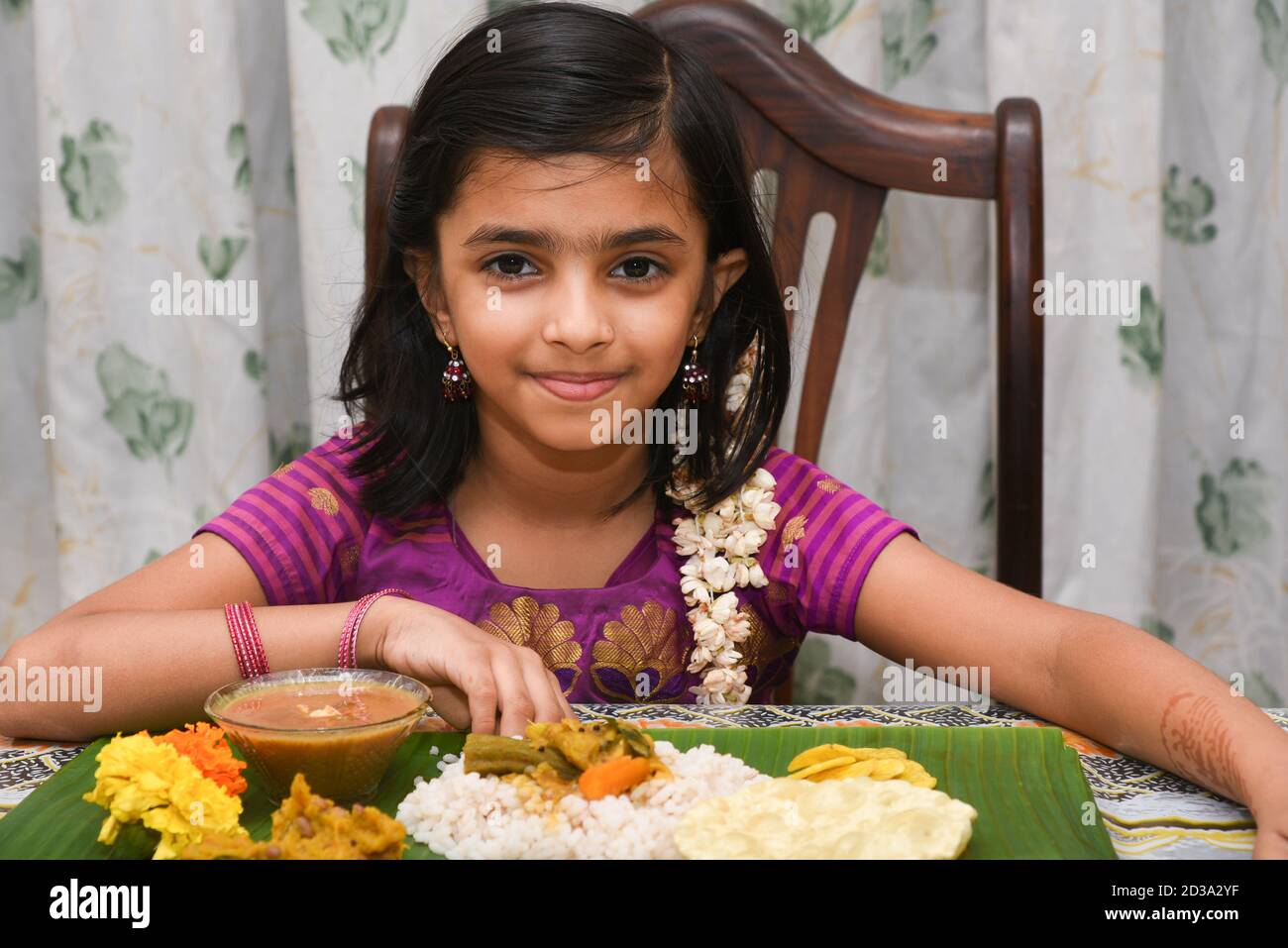 Festival de Kerala Onam, bonne fille indienne mangeant Onam sadhya avec la main portant la robe traditionnelle, Inde. Jeune enfant asiatique souriant. Bel enfant Banque D'Images