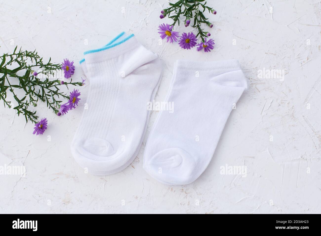 Deux paires de chaussettes et de fleurs pour femmes sur fond blanc structuré, vue du dessus. Banque D'Images