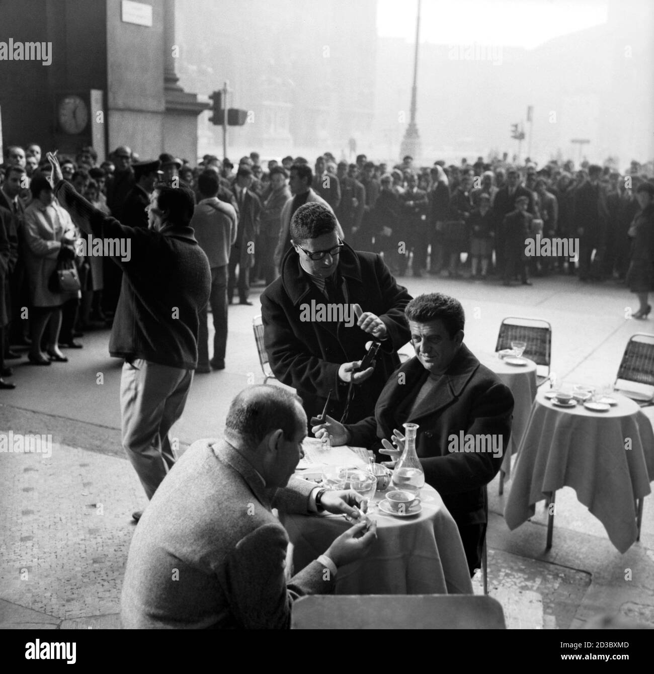 L'attore Vittorio Caprioli (di spalle) e il reganta Nanni Loy (Giovanni  Loi) seduti al tavolino di un bar dans la galerie Vittorio Emanuele II dans  una pausa durante la lavorazione del film '