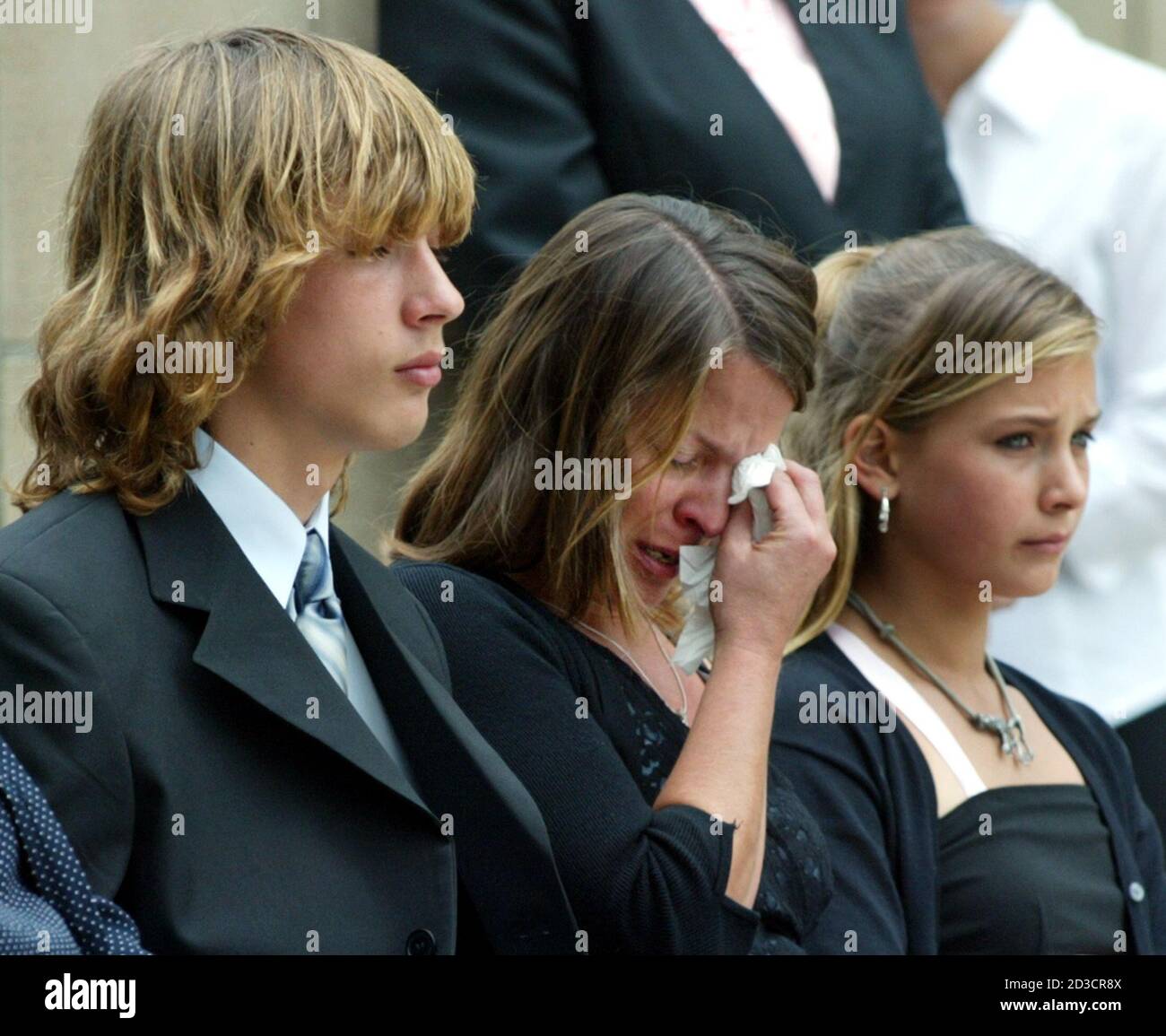 Fourteen-year old Kyle Helvenston (L) and twelve-year old sister Kelsey (R)  sit with their mother Tricia Irby (C) during a burial service for their  father and husband in Bushnell, Florida at the