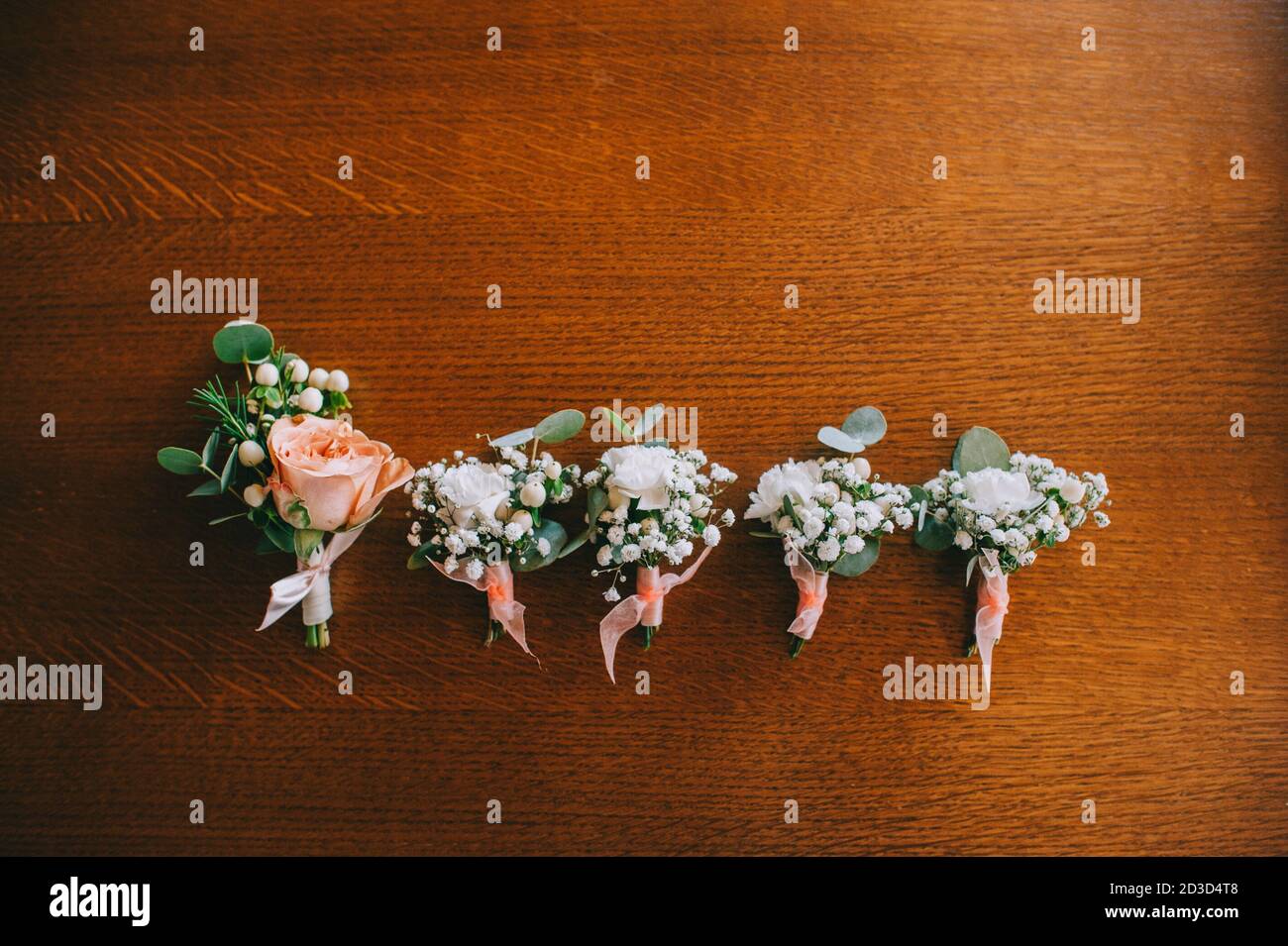Vue de dessus des élégantes boutonnières de mariage faites à la main dans des couleurs pastel sur une table laquée en bois. Détails de mariage avec espace de copie. Préparation pour le mer Banque D'Images