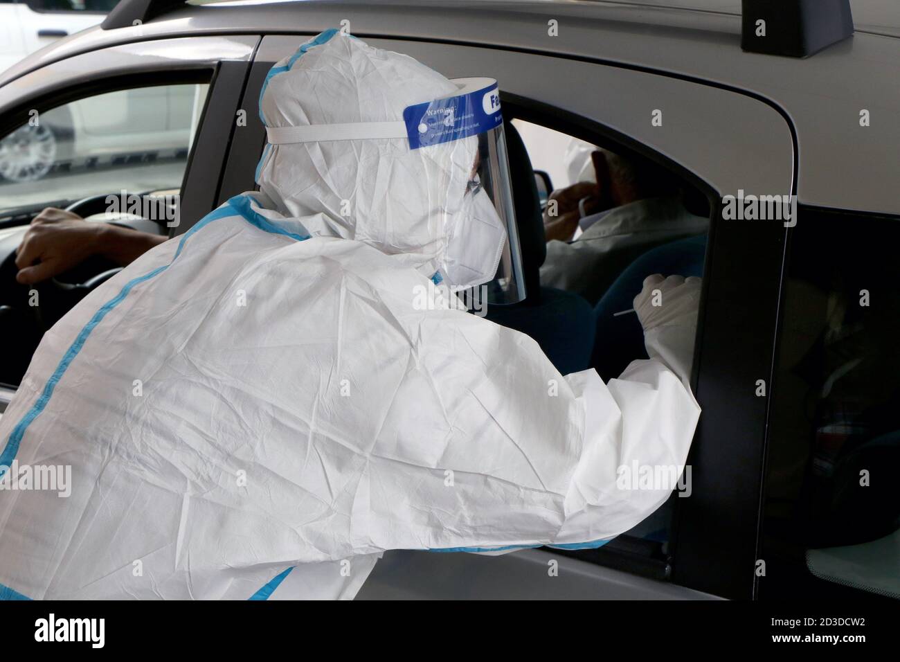 Les infirmières italiennes avec des combinaisons de protection, des masques et des gants font les écouvillons nasaux aux citoyens dans ses voitures en raison d'un cas possible de coronavirus Banque D'Images