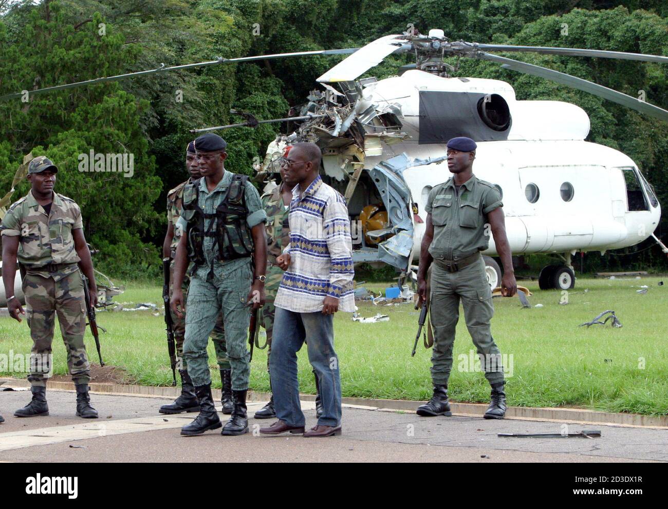 Colonel Phillipe Mangou chief commander of Ivory Coast military operation  (3rd from the right) is seen in front of a destroyed helicopter at the  presidential residence in Yamoussoukro, November 07, 2004. Ivory