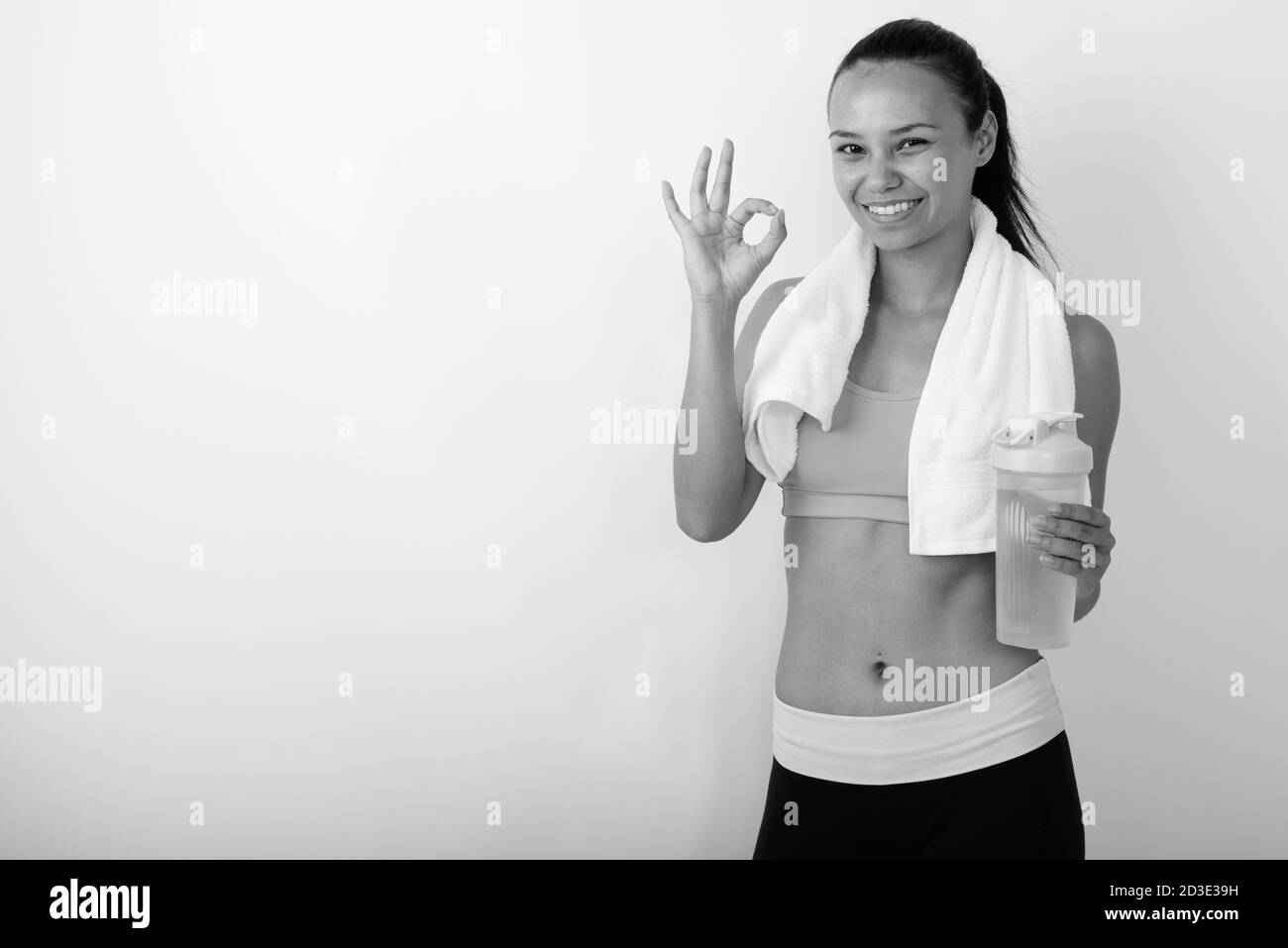 Bonne jeune femme asiatique donnant le signe ok et tenant l'eau bouteille prête pour la salle de sport Banque D'Images