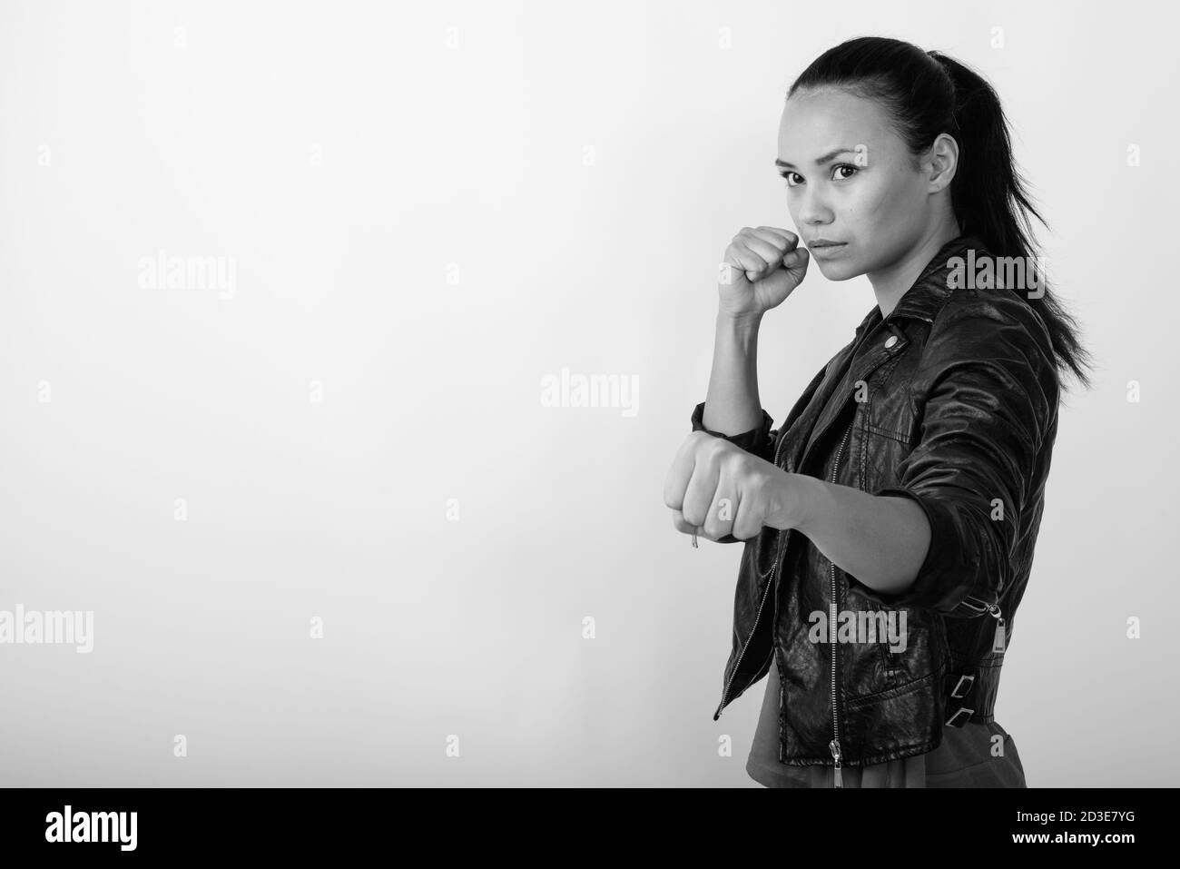 Photo studio d'une jeune femme asiatique qui regarde sur le côté avec les deux poings élevés prêts à se battre contre fond blanc Banque D'Images