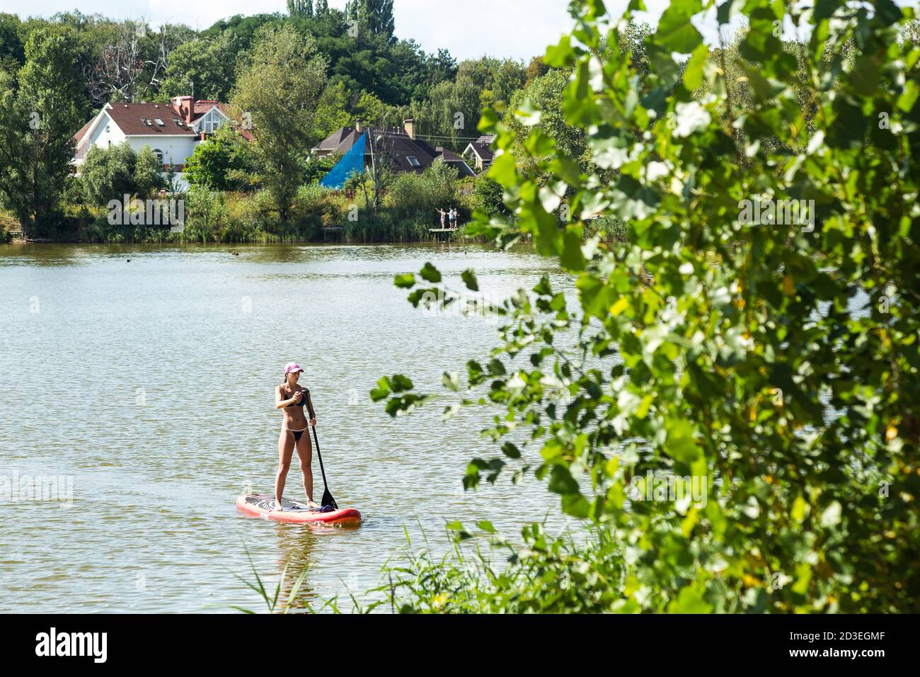 Une jeune femme en planche d'équilibrage se trouve sur les rives du lac Ministerka et de la zone de loisirs de Kiev, où nageurs, pagayeurs, marathoner train. Banque D'Images