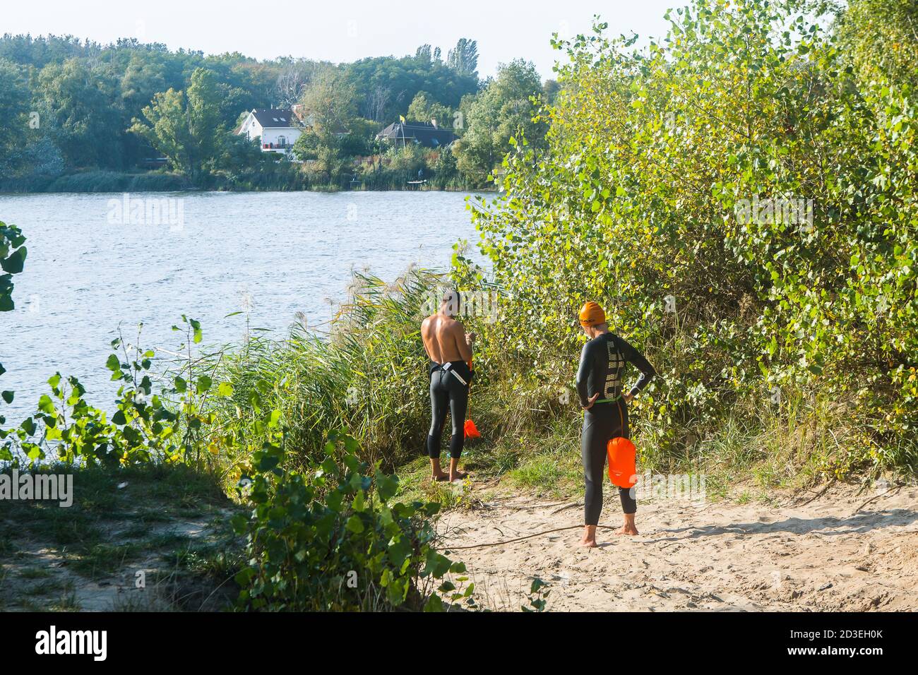 Le jeune homme en costume de plongée se prépare à plonger dans l'eau sur la rive de la région de Kiev, le lac Ministerka et la zone de loisirs, où les nageurs s'entraînent. Banque D'Images